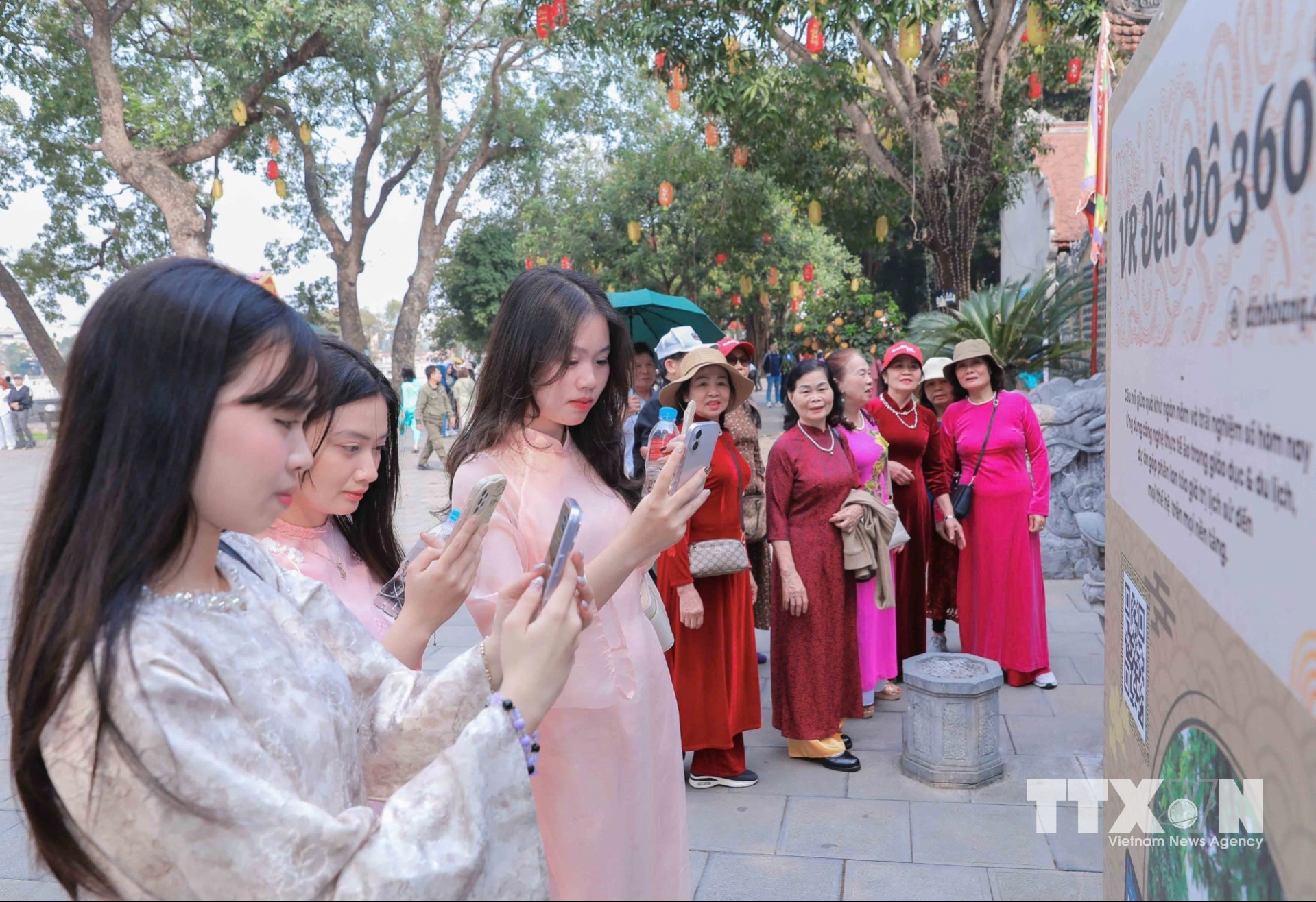 Các bạn trẻ sử dụng điện thoại thông minh truy cập thông tin số hóa về di tích và hành trình tham quan. (Ảnh: Phan Phương/TTXVN)